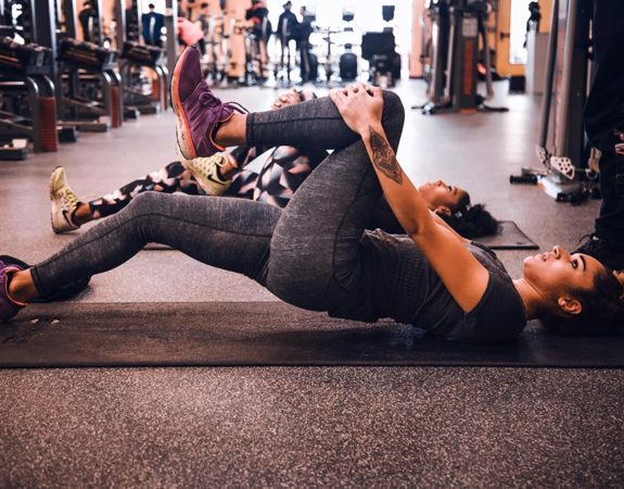 A woman laying on the ground and stretching as part of her physiotherapy treatment